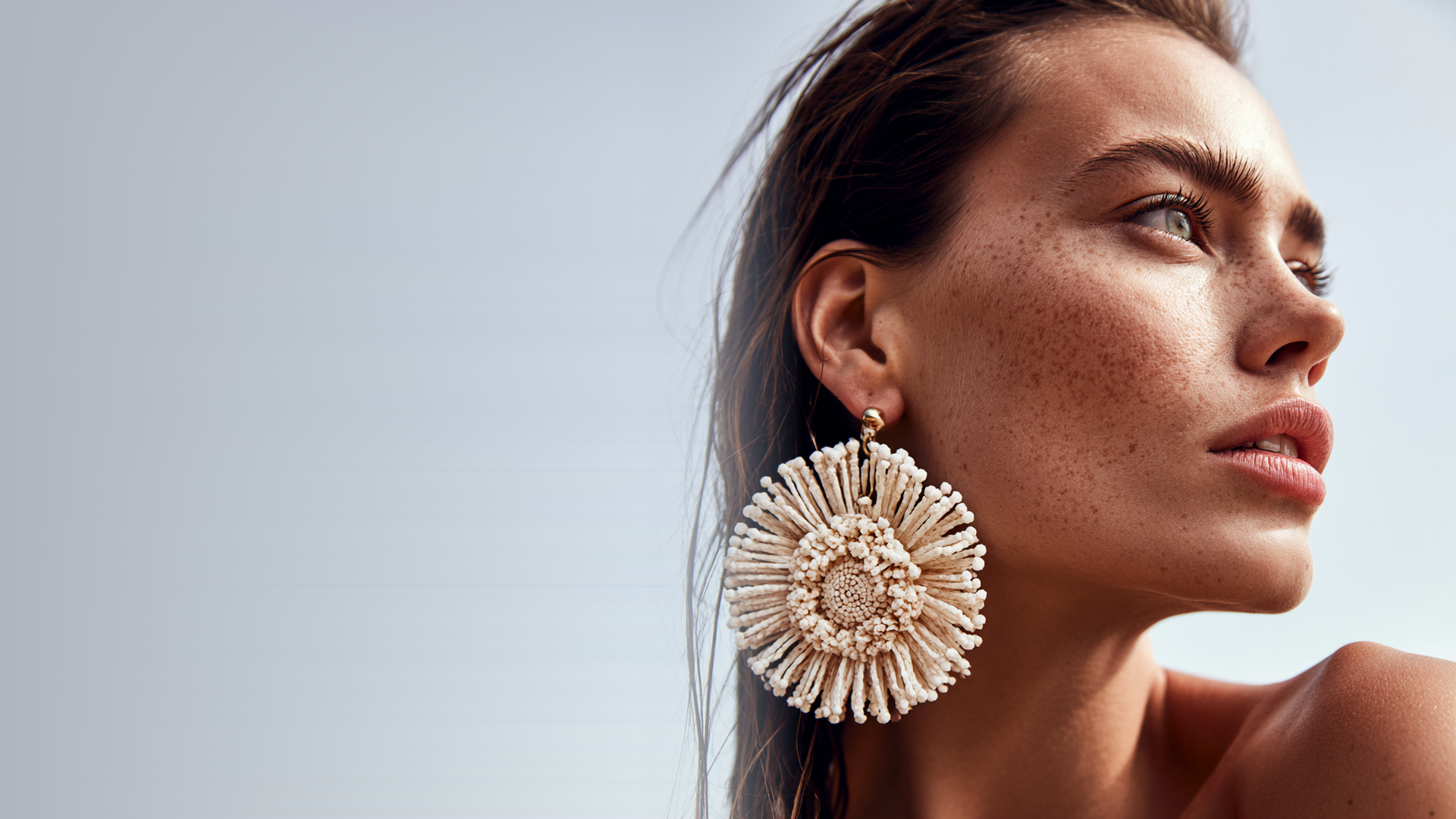 Woman wearing a handwoven cream statement earring by the beach - The Beauty Edit at Bondi Basics